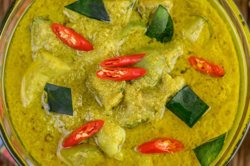 Poisson mijoté au curry vert avec morceaux, feuilles de curry, piments rouges, dans une sauce verte.