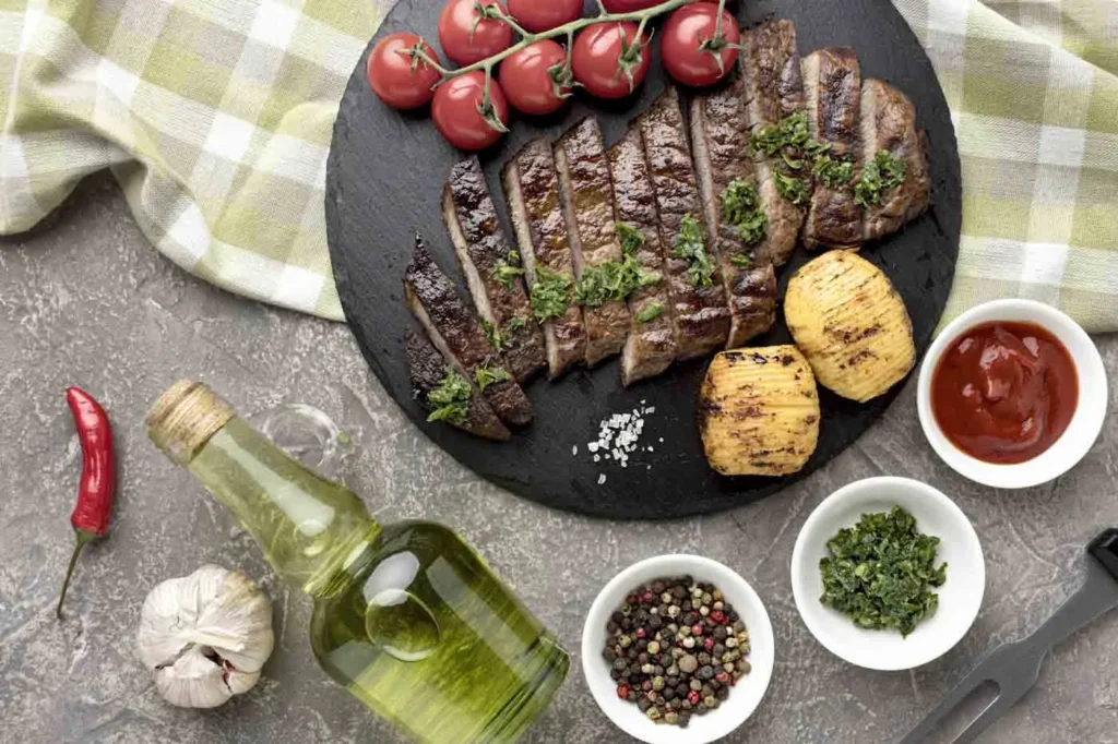 Entrecôte grillée avec tomates cerises, sauces, herbes, sel, poivre, ail, huile d'olive sur planche en ardoise.