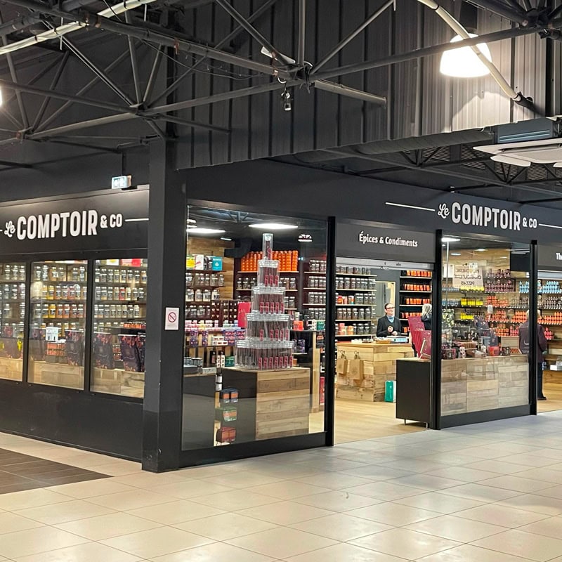 Vitrine de la boutique Comptoir & Co avec étagères de produits d'épicerie et épices en bocaux et sachets.