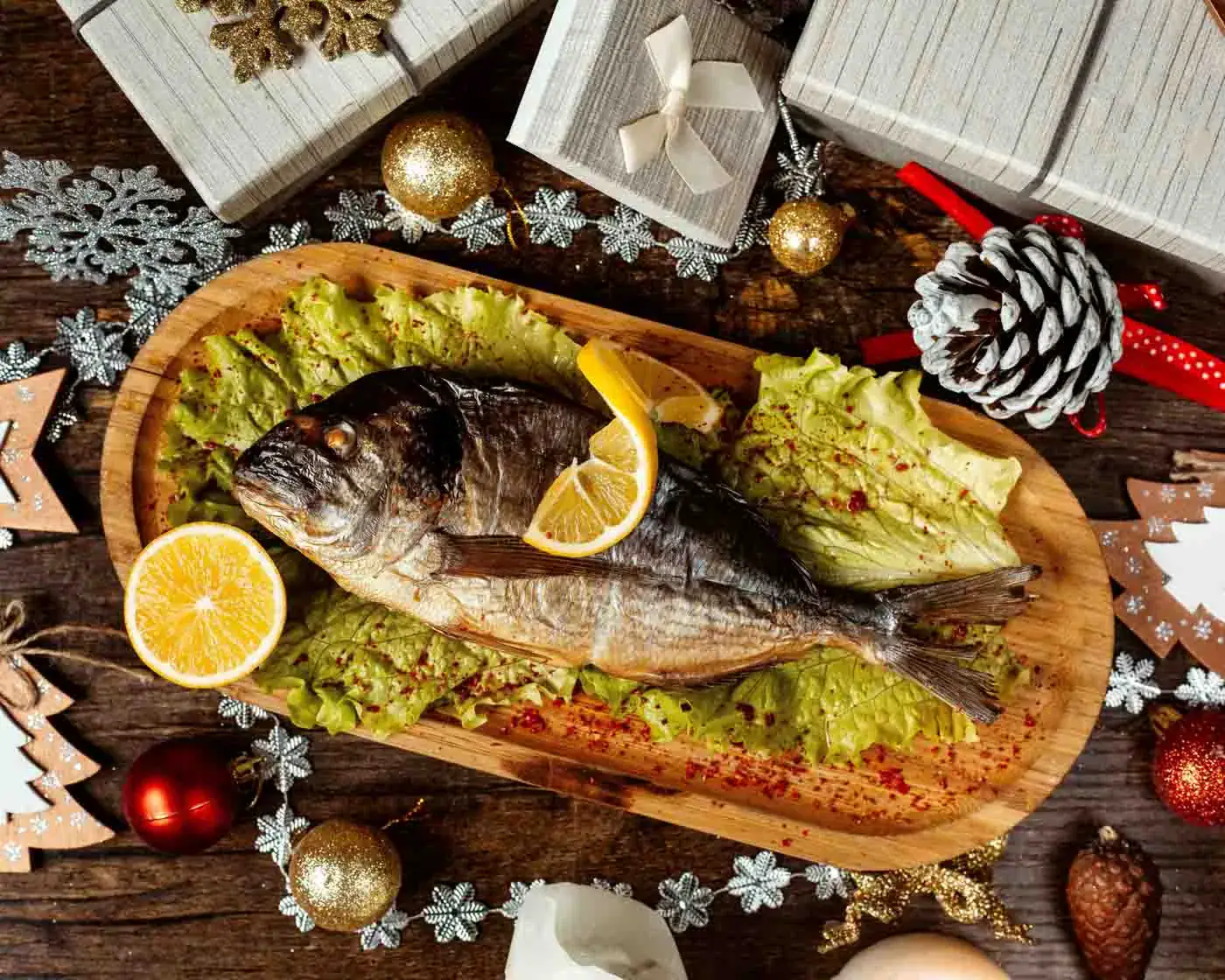 Daurade au poivre festif Poisson entier cuit avec citron sur un plat en bois, décoré de salade et d'épices, ambiance festive avec décorations de Noël.